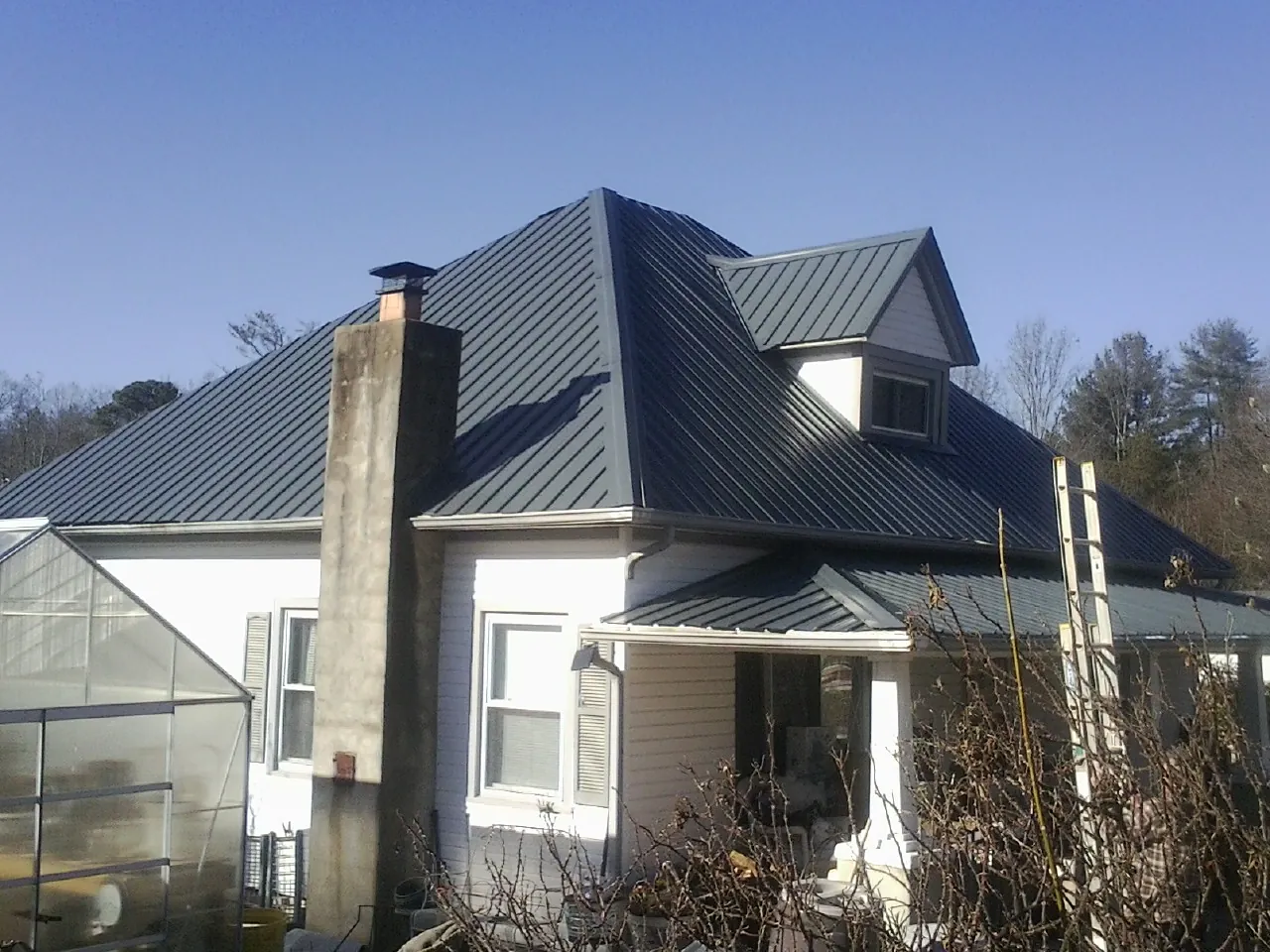 Dark blue standing seam metal roof on a white farmhouse with dormer — Slate & Tile Roof Repair by Roofing Brothers in Vinegar Bend