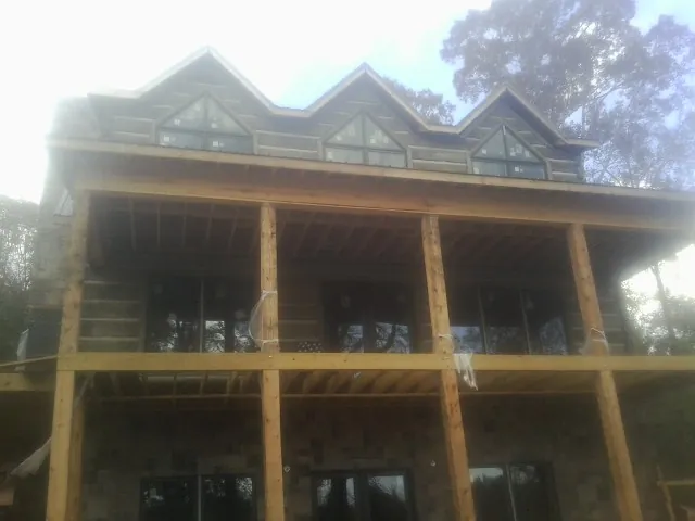 Dormers and porch framing on a large log home under construction — Roof Coating work by our crew in Vinegar Bend