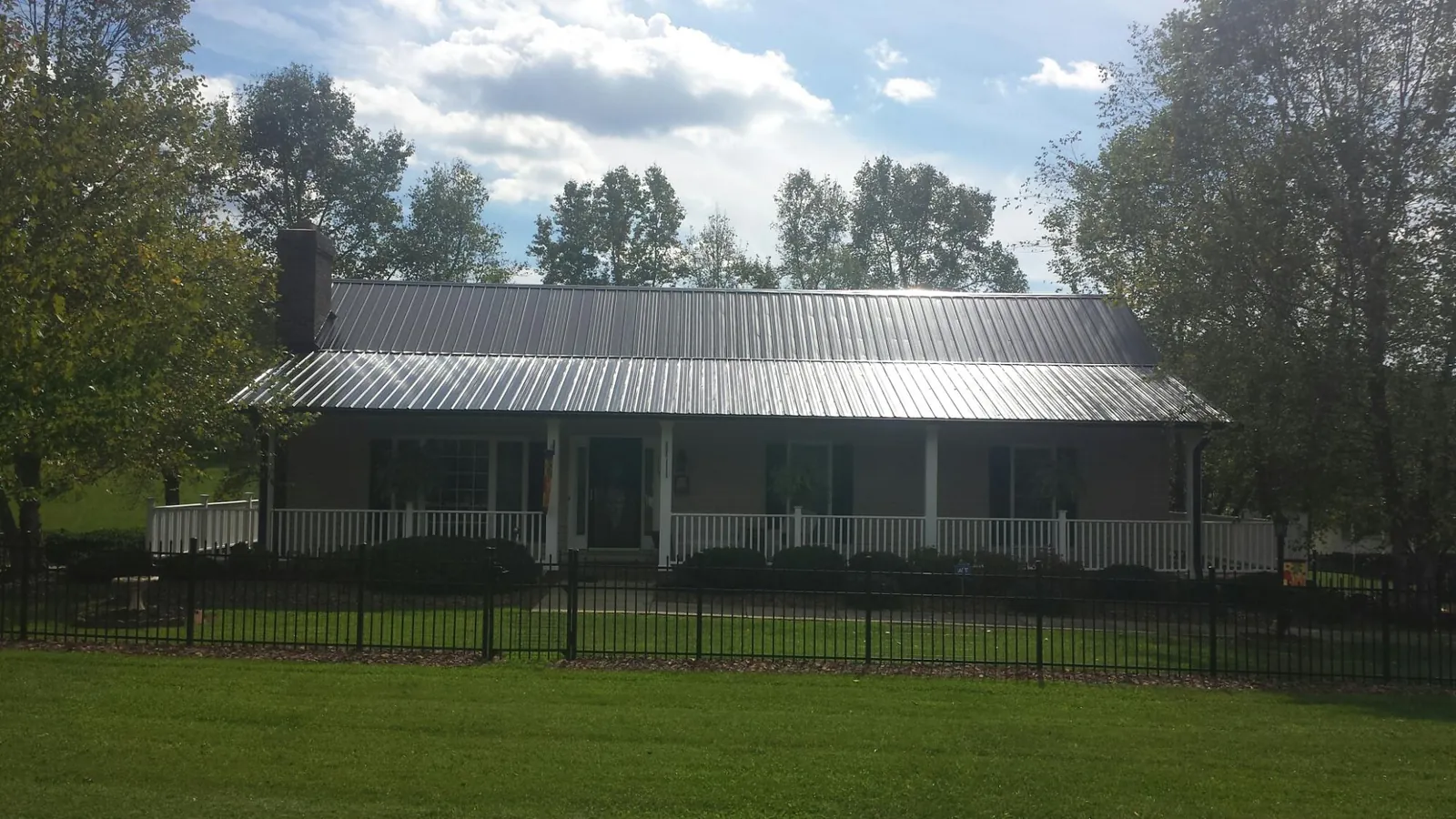Gray metal roof on a brick ranch with a full width front porch — Gutter Guard Installation work by our crew in Vinegar Bend