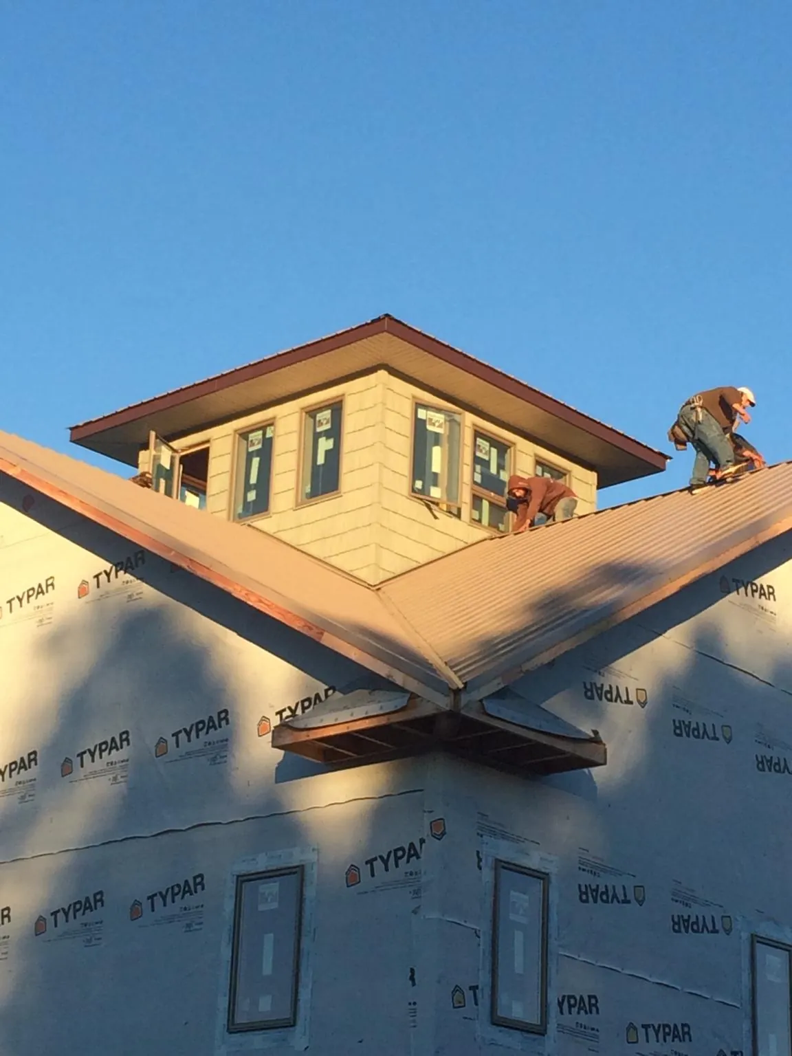 Roofers working around a rooftop cupola on a new metal roof at sunset — Roof Waterproofing in Vinegar Bend by Roofing Brothers